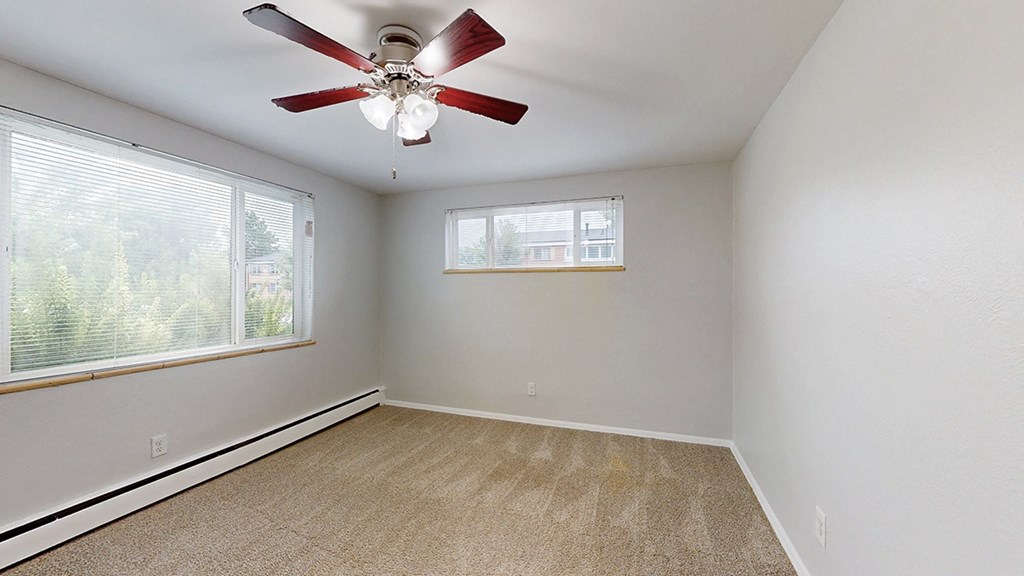 A room with a ceiling fan and a window with blinds.