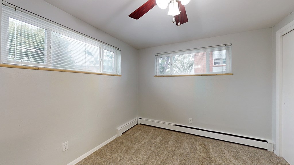 A room with a fan and two windows.