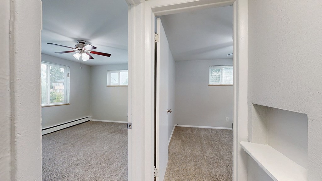 A room with a ceiling fan and carpeted floor.