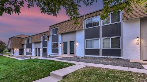 A row of modern townhouses with a sidewalk in front.