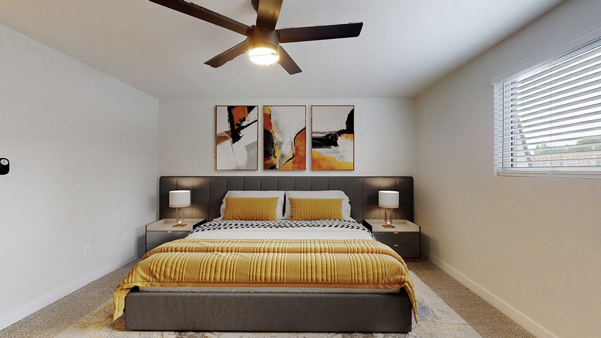 A bedroom with a bed, two lamps, and a ceiling fan.