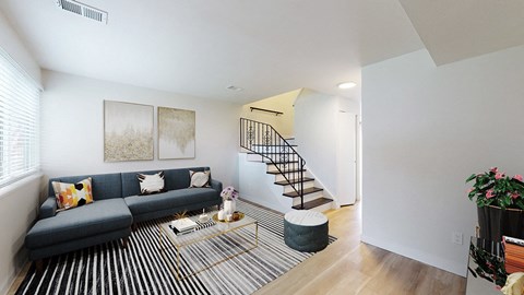 A living room with a blue couch and a glass coffee table.