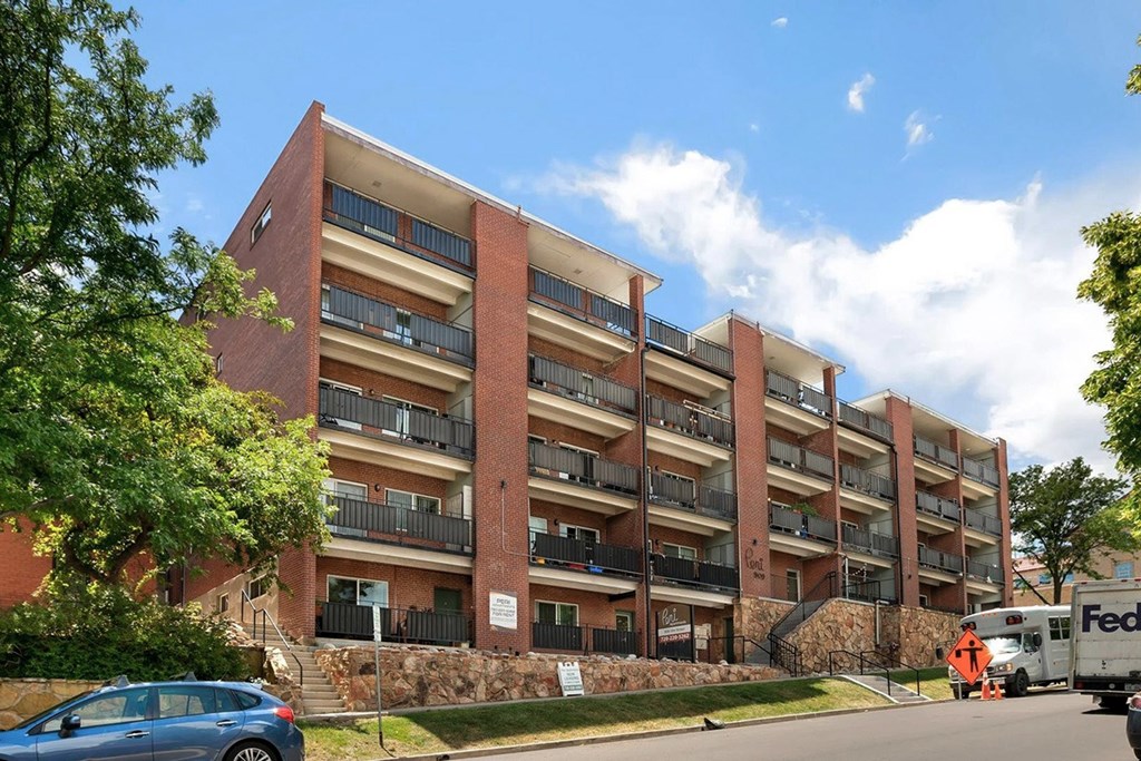 A large red brick building with a blue car parked in front.