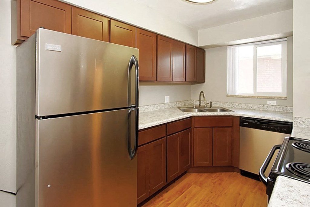 A kitchen with a stainless steel refrigerator and wooden cabinets.