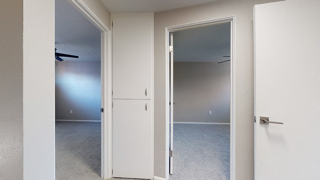 Two white doors in a room with carpeted floor.