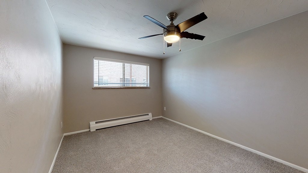 A room with a ceiling fan and a window.