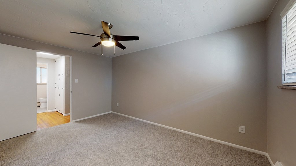 A room with a ceiling fan and carpeted floor.