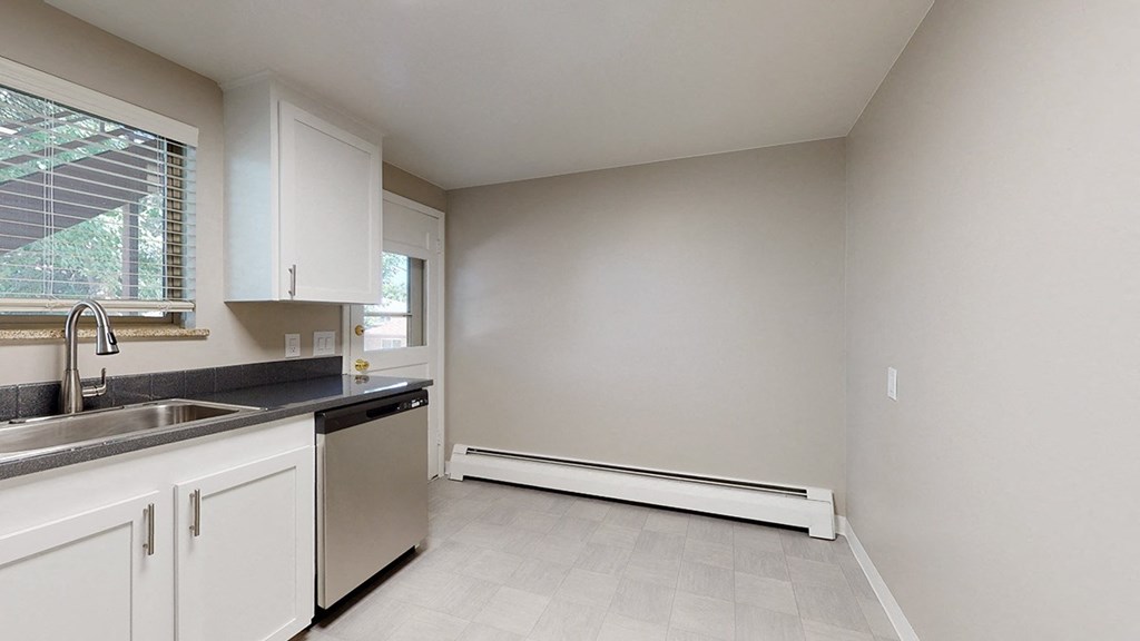 A kitchen with white cabinets and a black countertop.
