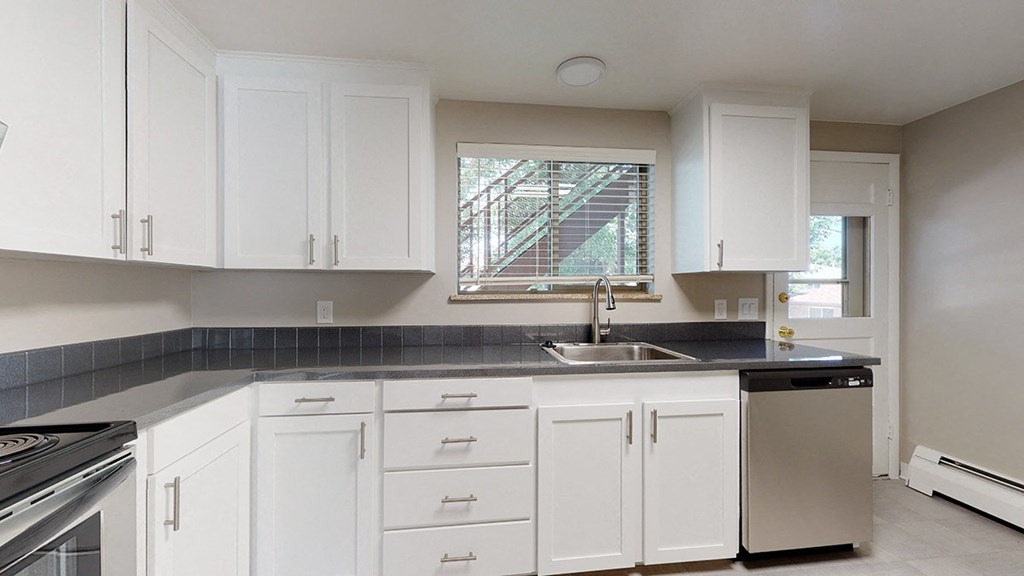 A kitchen with white cabinets and a black countertop.