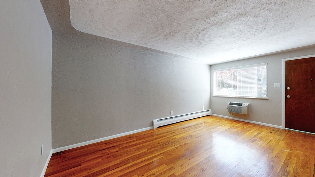 A room with wooden floors and a window with blinds.