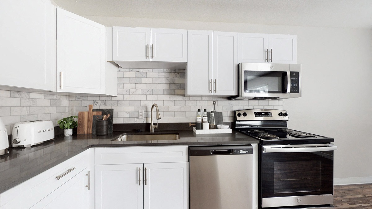 A modern kitchen with white cabinets and stainless steel appliances.