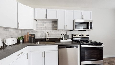 A modern kitchen with white cabinets and stainless steel appliances.