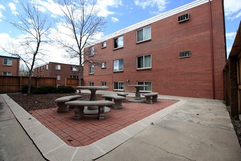 A red brick building with a concrete patio and tables.
