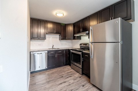 A modern kitchen with dark wood cabinets and stainless steel appliances.