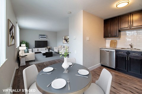 A modern dining room with a grey table and white chairs.