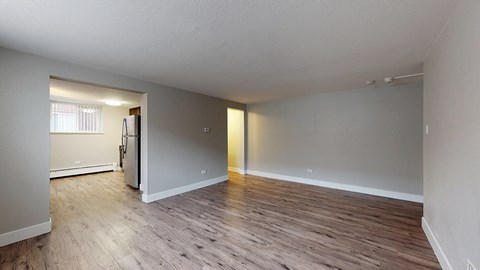 A spacious room with wooden flooring and white walls.
