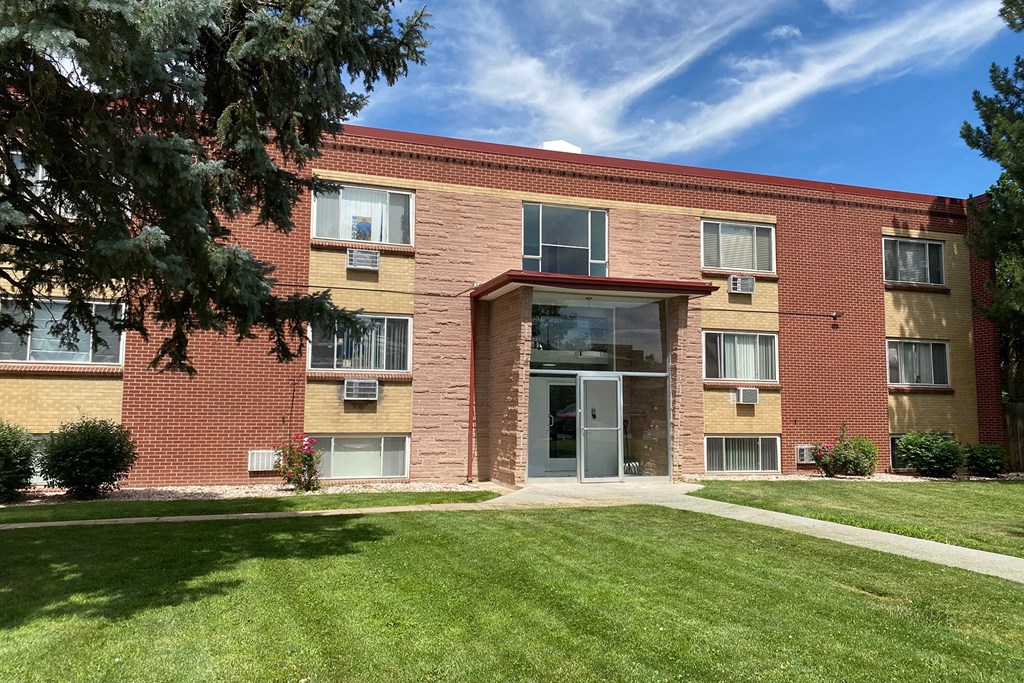 A red brick building with a green lawn in front.