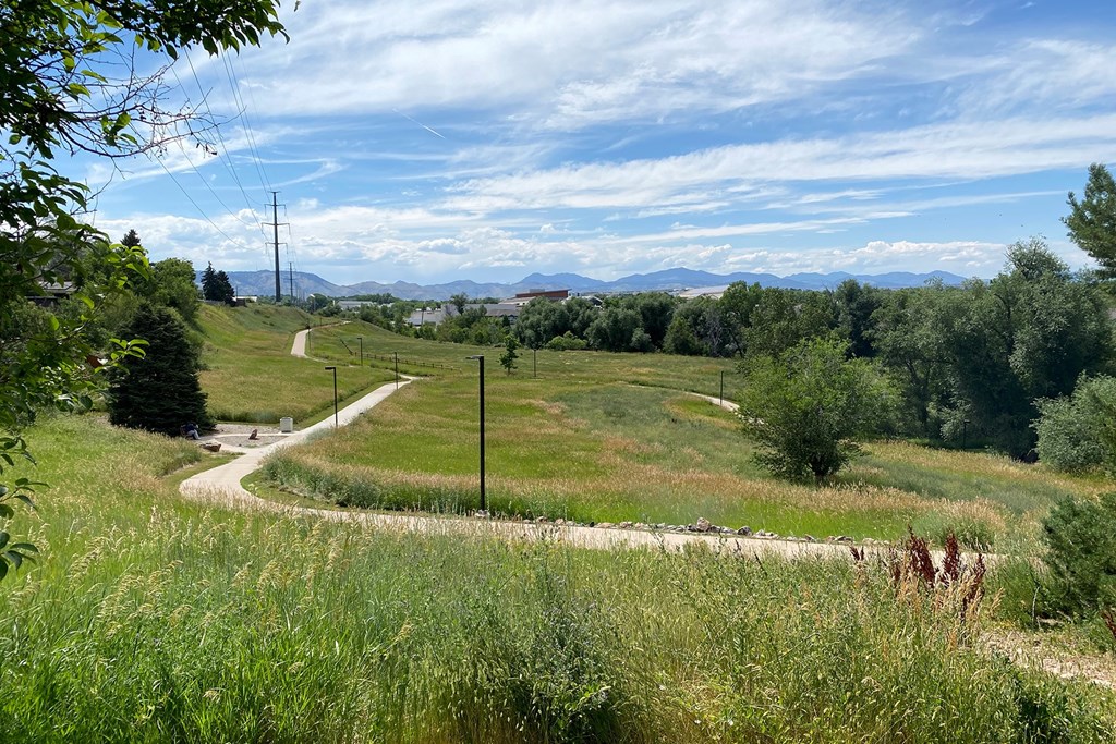 View of mountains from Sunset Park. Grassy field in distance with concrete trail.