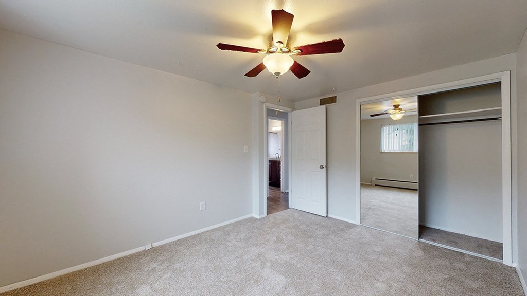 Bedroom with a ceiling fan, carpeted floor and closet with sliding door.