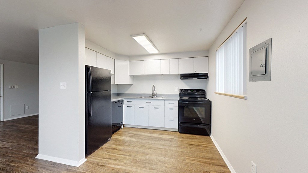 A kitchen with black appliances and white cabinets.