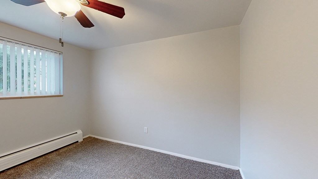 A room with a ceiling fan and a window with blinds.
