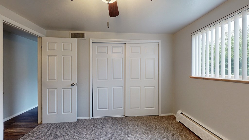 A room with two doors and a window with blinds.