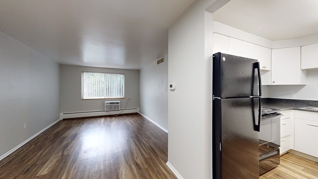 A black fridge in a kitchen with white cabinets.