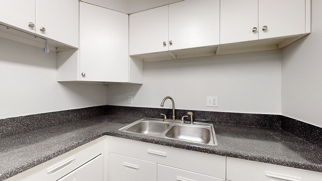 A kitchen with white cabinets and a granite countertop.