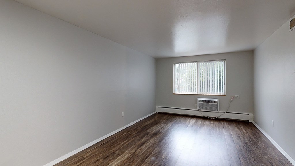 A room with wooden floors and a window with blinds.