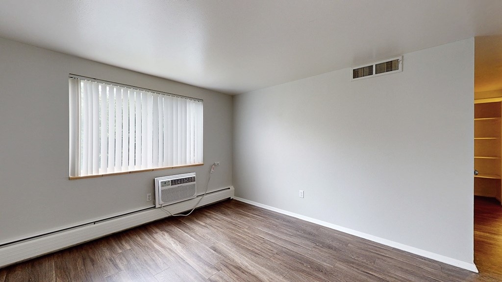 A room with a window and wooden flooring.