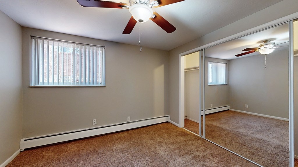 A room with a ceiling fan and a window with blinds.