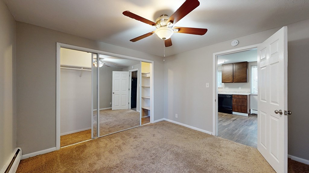 A room with a ceiling fan and carpeted floor.