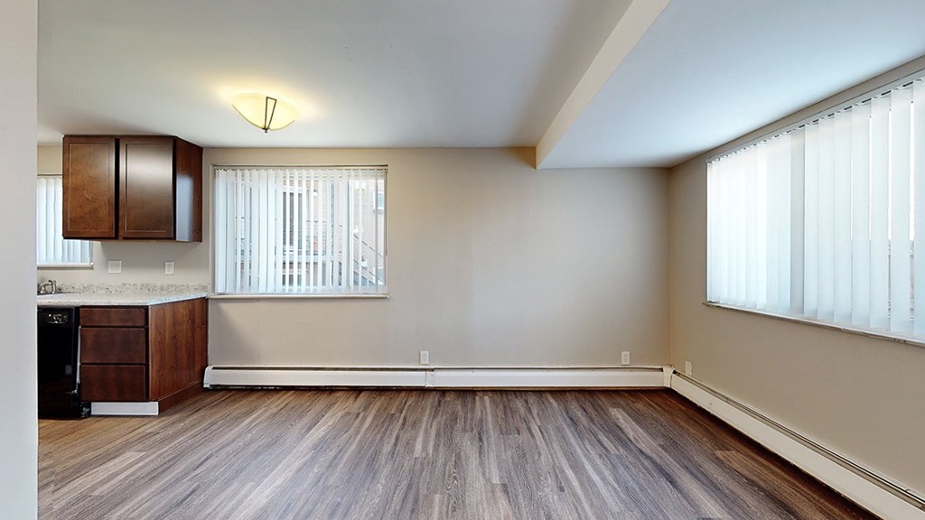 A room with wooden floors and a window with blinds.