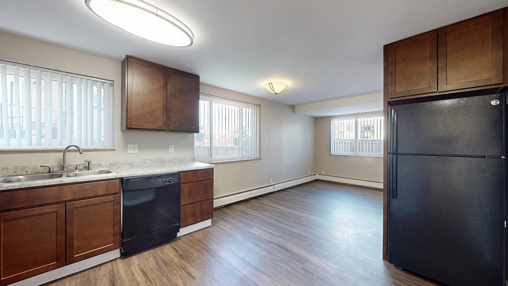 A kitchen with a black fridge and wooden cabinets.