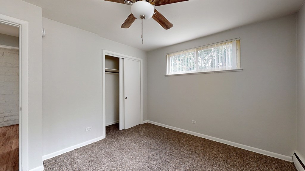 A room with a ceiling fan and a window with blinds.