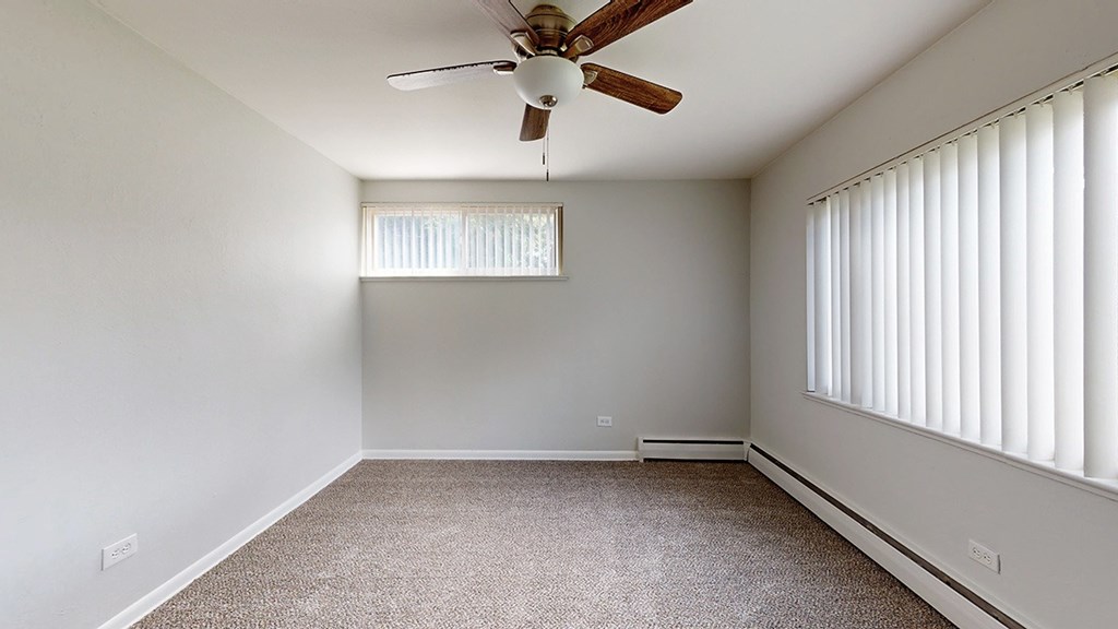 A room with a ceiling fan and a window with blinds.