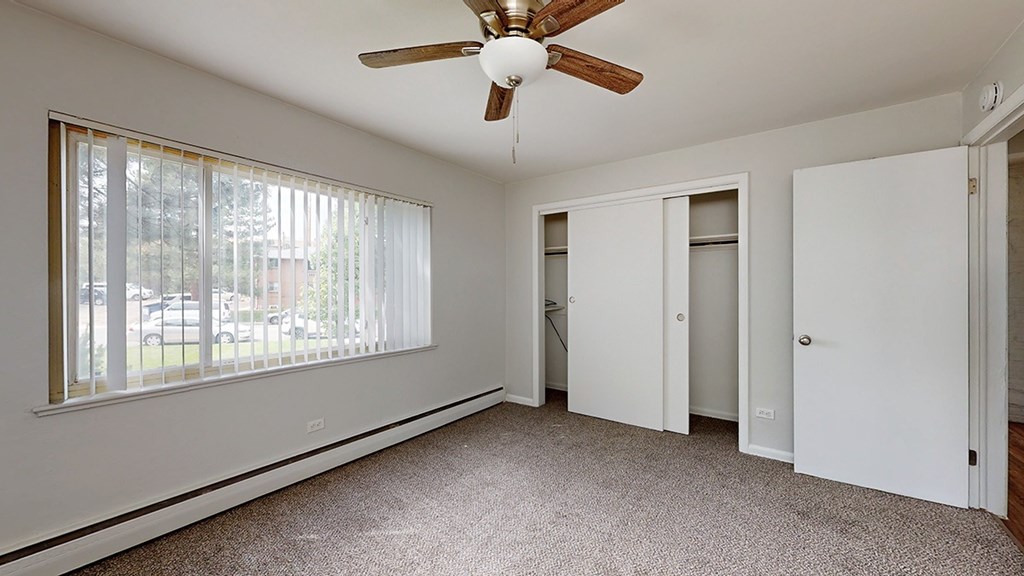 A room with a ceiling fan and carpeted floor.