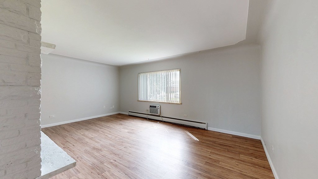 A room with wooden flooring and a window with blinds.