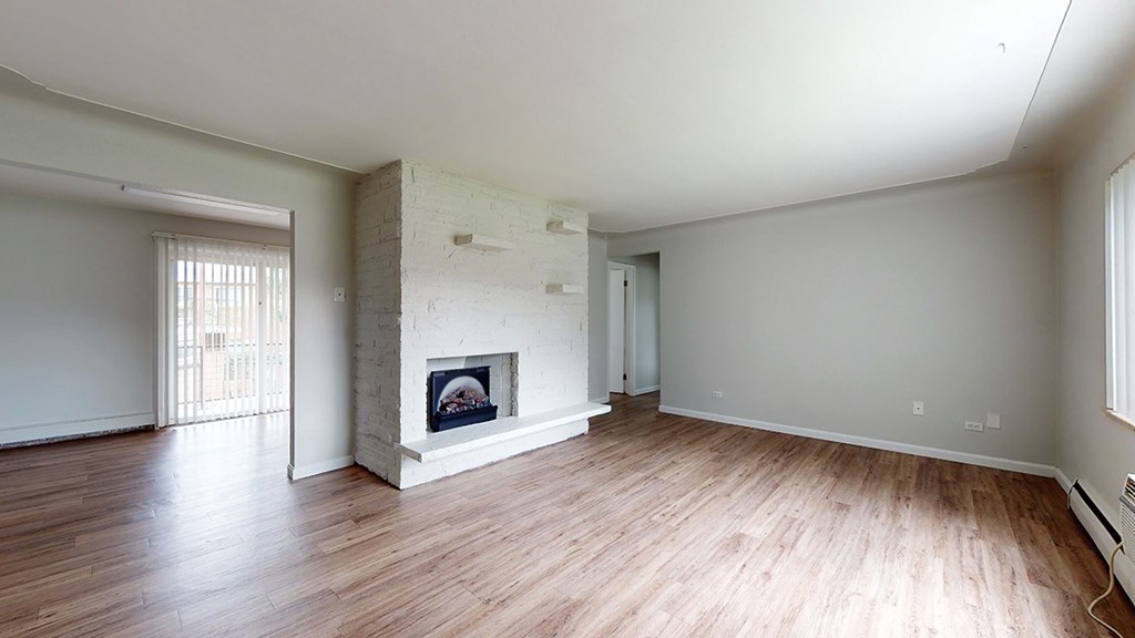 A room with a fireplace and wood flooring.