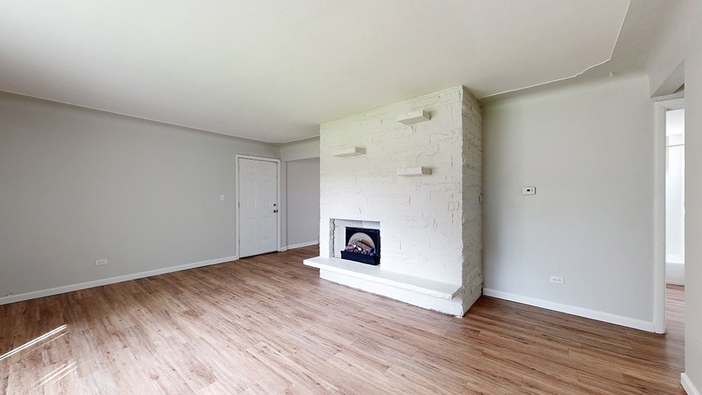 A white room with a fireplace and wooden floors.