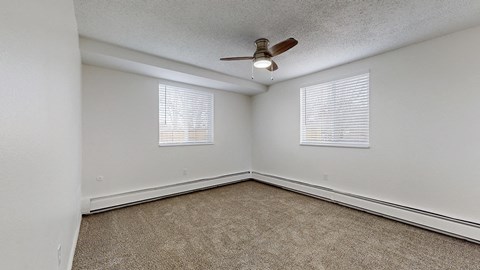 A room with a ceiling fan and carpeted floor.