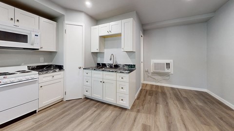 A kitchen with white cabinets and a wooden floor.