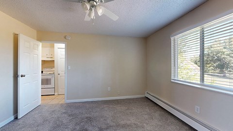 A room with a ceiling fan and a window with blinds.