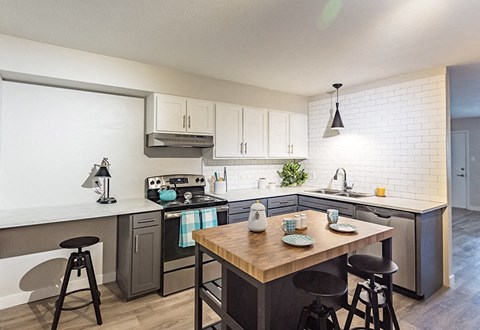 A kitchen with a wooden table and black stools.