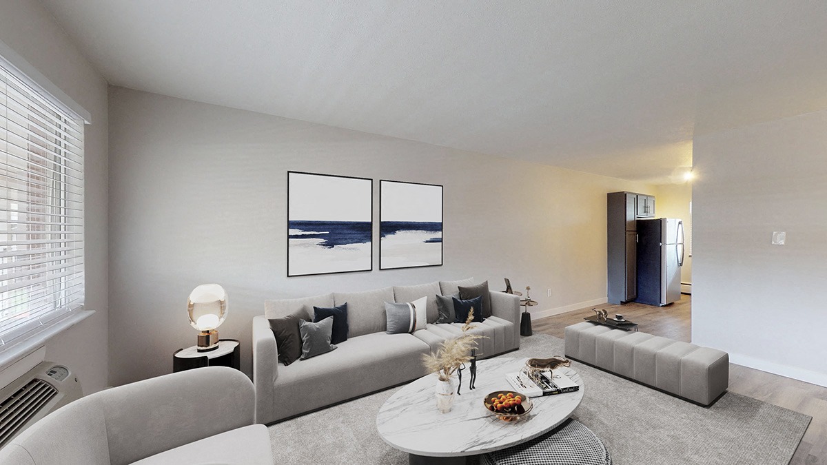 A modern living room with a grey couch, a white coffee table, and a painting on the wall.