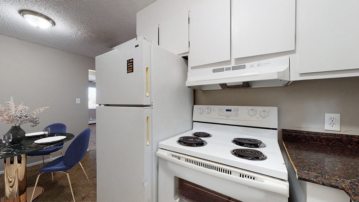 A white stove and refrigerator in a kitchen with a table and chairs.