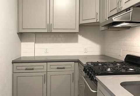 A kitchen with white cabinets and a black stove top.