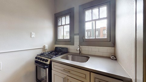 A kitchen with a stove, sink and window.