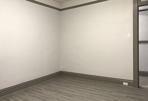 A room with a grey floor and a white wall with a switch.