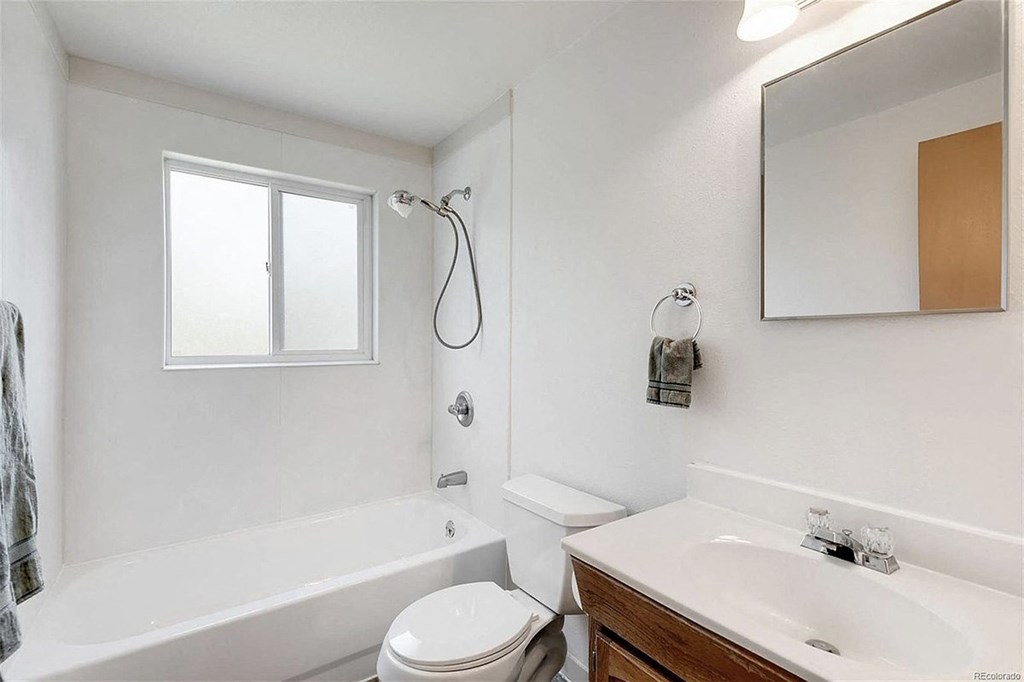A white bathroom with a toilet, sink, and bathtub.